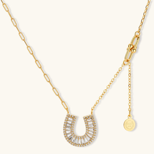 Sparkling horseshoe-shaped jewelry set with AAA cubic zirconia in gold-plated and white gold finishes on cream background.