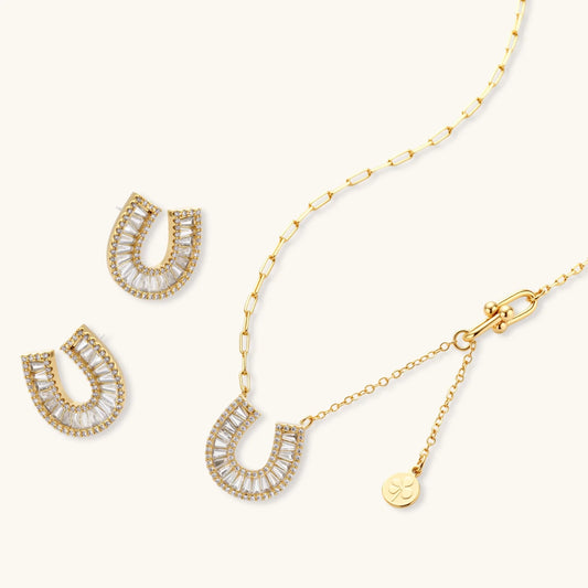 Sparkling horseshoe-shaped jewelry set with AAA cubic zirconia in gold-plated and white gold finishes on cream background.