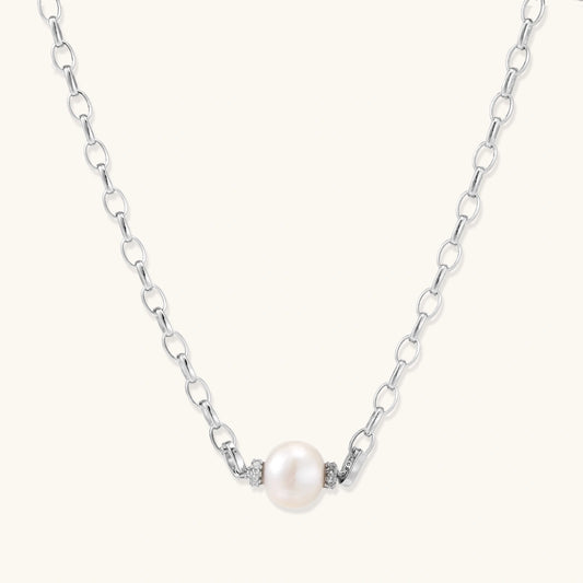Dainty rhodium-plated silver chain necklace with centered 10mm freshwater pearl and crystal accents on cream background