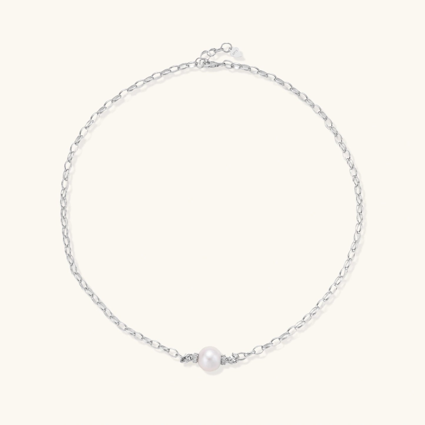 Dainty rhodium-plated silver chain necklace with centered 10mm freshwater pearl and crystal accents on cream background