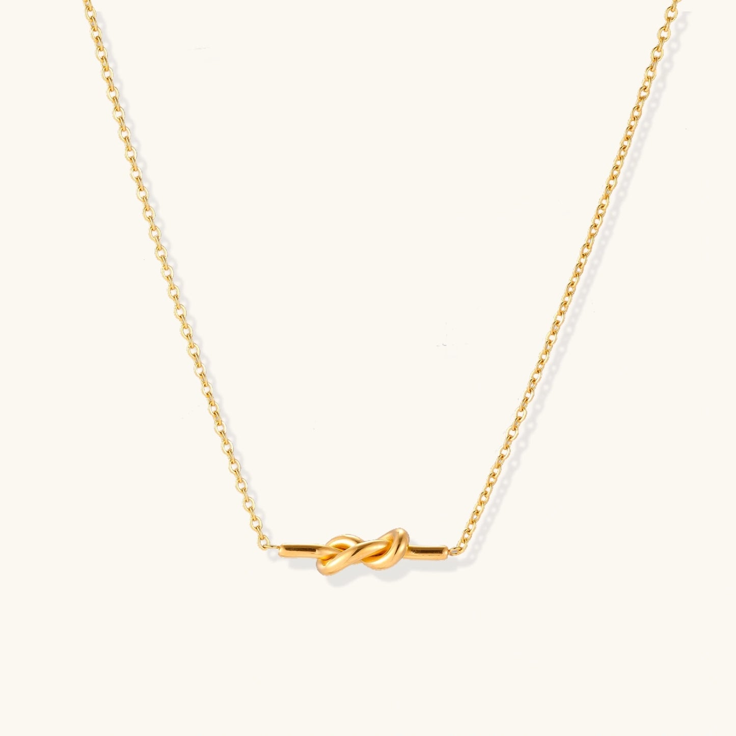 Dainty 18K gold plated necklace with infinity knot pendant on delicate chain against white background