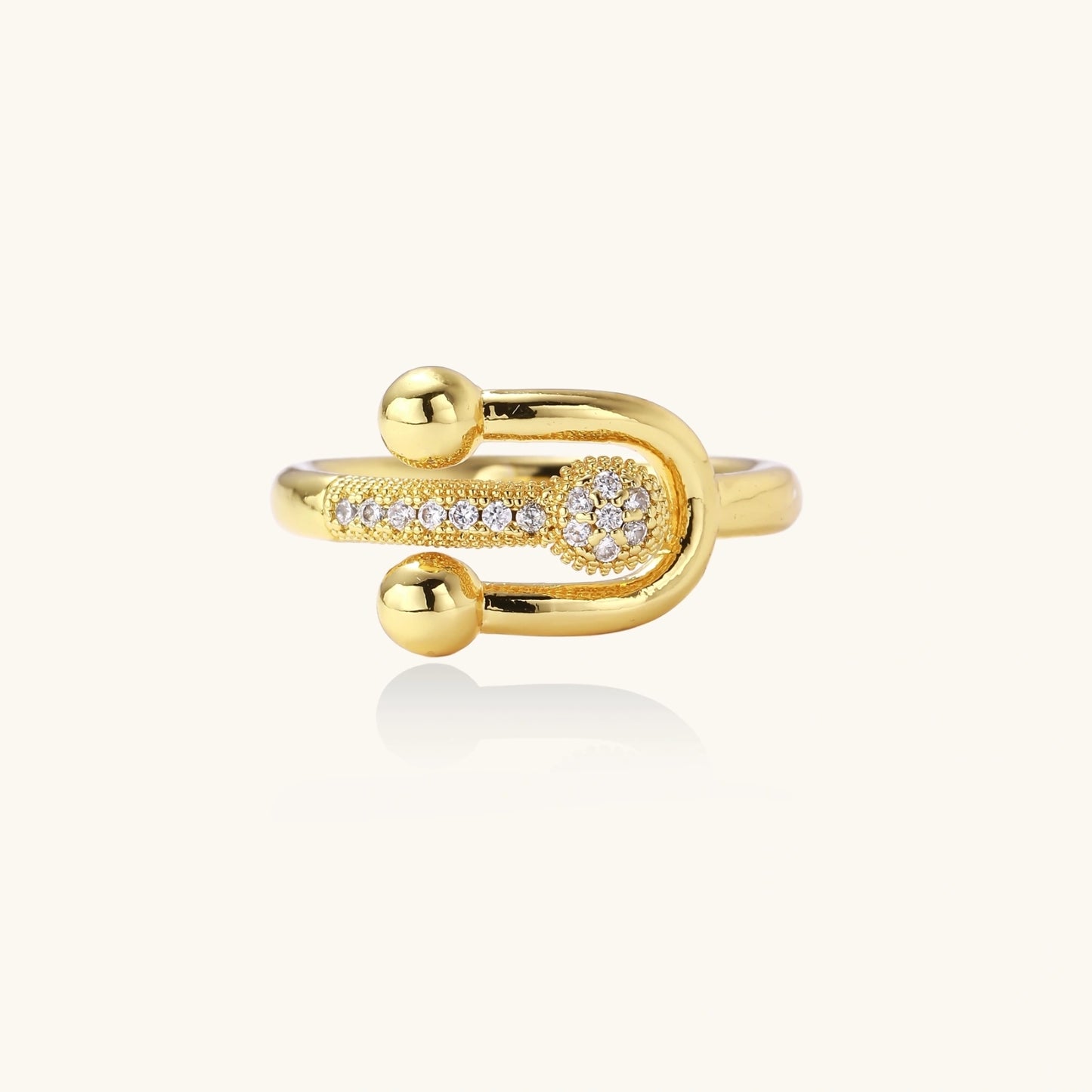 Gold-plated brass ring with safety pin design featuring pavé cubic zirconia stones and dual sphere ends